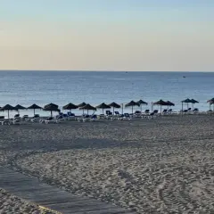 Playa marina de la torre con arena fina y tumbonas bajo sombrillas. El mar tranquilo se extiende hasta el horizonte.