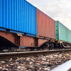 Długi pociąg towarowy z kolorowymi kontenerami na torach. To przykład transportu kolejowego, który jest kluczowy dla globalnej logistyki.