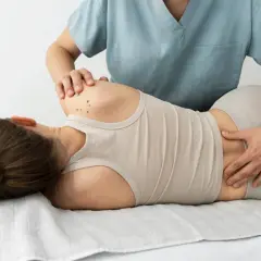 Fizjoterapeuta bada plecy pacjentki, szukając przyczyn bólu. Czy to dyskopatia, co to jest?