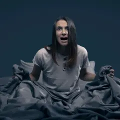 Mujer en la cama, con expresión de angustia, sujetando las sábanas. Parece que se despierta sobresaltada porque me encuentro mal por las mañanas.