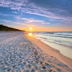 Zachód słońca nad morzem, piaszczysta plaża z odciskami stóp, las w tle. Idealne, fajne miejsce nad morzem dla dwojga na romantyczny spacer.
