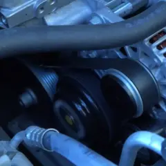 La correa de distribución se ve girando en el motor, conectando el alternador y otras poleas.