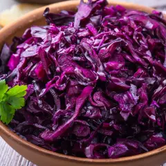 Pyszna surówka z czerwonej kapusty jak w restauracji, podana w glinianej misce z gałązką pietruszki i kromkami chleba.