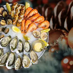 Plateau de fruits de mer frais, une tradition de Noël en France, avec huîtres, crevettes, moules et bigorneaux, sur un lit de glace, décoré de citrons et d'une sauce.