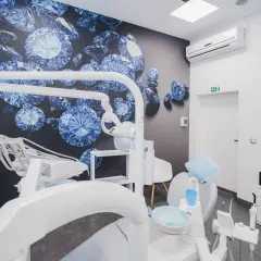 Nowoczesny gabinet stomatologiczny z fotelem dentystycznym i tapetą z niebieskimi diamentami.