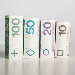 Zrolowane banknoty 100, 50, 20 i 10 złoty symbolizują potencjalną rentowność inwestycji.