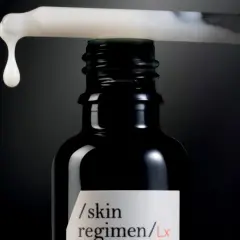 Una goccia di siero cade da un contagocce su una bottiglia scura, un passo essenziale nelle fasi skincare per una pelle radiosa.