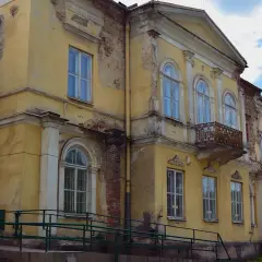 Żółty, zniszczony budynek z balkonami i łukowymi oknami, wymagający pilnej ochrony konserwatorskiej.