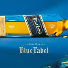 Elegancka butelka Johnnie Walker Blue Label leży na niebieskim tle. Złoty płyn i niebieskie szkło tworzą luksusowy kontrast.