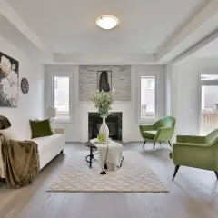 Salon moderne avec canapé blanc, fauteuils verts et cheminée. Le tapis et les coussins apportent une touche de blanc cassé.
