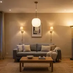 Une ampoule salon design éclaire ce salon cosy avec un canapé gris, une table basse en bois et une plante verte.