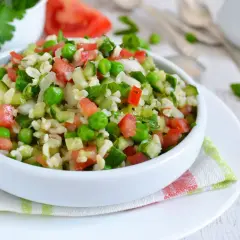 Orzeźwiająca sałatka z kaszą bulgur, pomidorami, ogórkiem i zielonym groszkiem, doprawiona fetą.