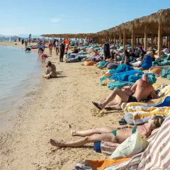 Ludzie odpoczywają na plaży w Egipcie. Idealna pogoda w Egipcie w grudniu sprzyja relaksowi na leżakach pod palmowymi zacienionymi wiatami.