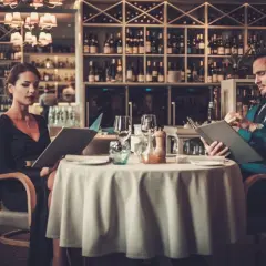 Elegancka para przy stoliku w restauracji, przeglądająca karty dań. Krótki dialog w restauracji po angielsku w tle.