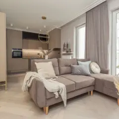 Nowoczesny salon z aneksem kuchennym. Sofa w odcieniu **kolor piaskowy z czym łączyć** – tu z szarościami i beżami.