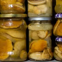 Słoiki z grzybami w zalewie, gotowe do zimowych zapasów. Pyszna marynata do grzybów czeka na otwarcie.