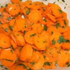Una deliciosa ensalada de zanahoria cortada en rodajas finas y aderezada con perejil fresco.