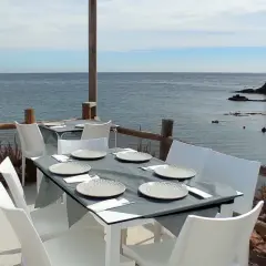 Mesas puestas en el restaurante La Isleta, listas para disfrutar de la brisa marina y un buen plato.