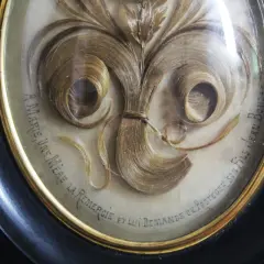 Intricate hair art in a framed oval, featuring swirling locks of blonde hair arranged like a floral bouquet. Text reads "A Marie, une mère la remercie et lui demande de protéger son fils Jean Boudet.