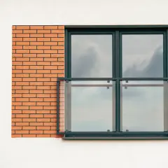 Nowoczesne balkony francuskie z przeszklonymi balustradami i ceglanym detalem na białej elewacji.