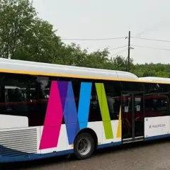 Autobus z kolorowym logo i napisem "Małopolska" na tle drzew.