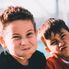 Dwóch chłopców robi śmieszne miny. To obraz rozwoju emocjonalnego 11 latka, który uczy się wyrażać siebie.