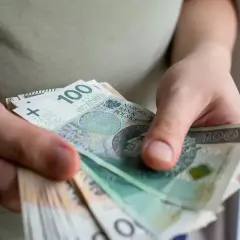 Dłonie trzymające stos banknotów 100 zł. Może to być pomoc de minimis dla przedsiębiorcy.
