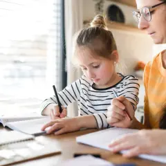 Dziewczynka z mamą uczą się w domu. Jak zacząć edukację domową? Skupienie na nauce i wsparcie rodziców.