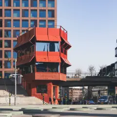 Rött, unikt hus vid Sergels torg, med trappor och moderna byggnader runtom. En plats för bio och möten.
