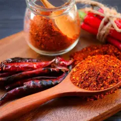 Ein Holzlöffel voller Cayennepfeffer-Flocken zeigt, woraus Cayennepfeffer hergestellt wird: getrocknete Chilischoten.