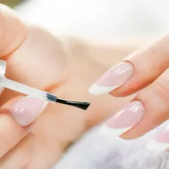 Mani curate che si preparano a fare unghie perfette con smalto trasparente.