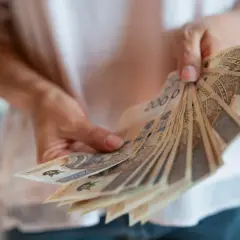 Dłonie trzymają wachlarz banknotów 200 zł. To symbol nagrody jubileuszowej za 40 lat pracy w budżetówce.