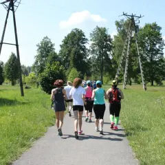 Grupa kobiet biegnie ścieżką w parku, uczestnicząc w obozach bieganie.