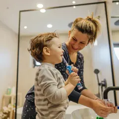 Mama pomaga synkowi myć zęby, by pozbyć się nieprzyjemny zapach z ust dziecka.