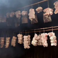 Mięsa zawieszone w dymie, gotowe do wędzenia na gorąco. Tradycyjny proces nadający smak i aromat.