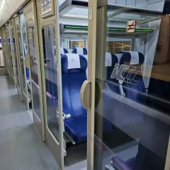 Wnętrze pociągu Intercity. Widać rząd niebieskich siedzeń i drzwi. Na szybie znak zakazu palenia, więc nie ma palarni.