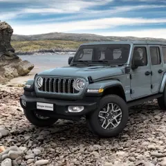 Szary Jeep Wrangler Unlimited na kamienistej plaży. Idealny na przygodę, rozważ jeep leasing.