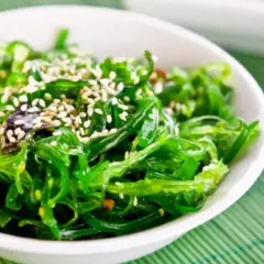 A vibrant green seaweed salad, sprinkled with sesame seeds, perfect for healthy kelp recipes.