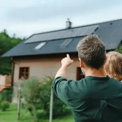 Padre e figlia guardano il tetto con pannelli solari. Un impianto fotovoltaico da 5 kW può produrre molta energia al giorno.