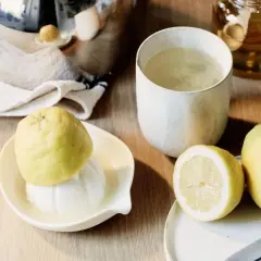 Zitronentee bei Halsschmerzen: frische Zitronen, ein Glas Tee und Honig auf einem Holztisch.