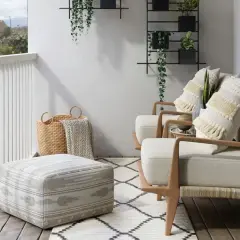 Przytulne **mały balkon aranzacje**: dwa fotele, puf, kosze i rośliny tworzą relaksującą przestrzeń.