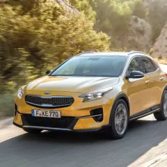 Żółty Kia XCeed na krętej drodze. Wiele osób szuka kia xceed opinie, ten model wygląda obiecująco.