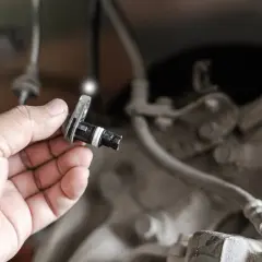 Mano che tiene un sensore ABS, componente essenziale per la sicurezza del veicolo.