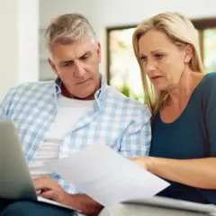 Para dowiedzieć się, jak wydrukować księgę wieczystą, analizuje dokumenty na laptopie.