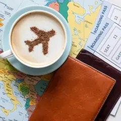 Une tasse de café avec un avion en cacao sur une carte du monde, à côté de billets d'avion. L'idée d'un voyage, d'une carte pass et étape.