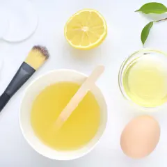Ingredientes para una mascarilla casera para el pelo seco y encrespado: huevo, limón, aceite y aplicador.