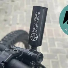 Close-up of a bicycle's mineral oil brake system with a "Neutron Components" tool attached.