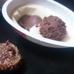 Lody Kinder Joy w białym opakowaniu z czekoladową kulką i kawałkiem waflowym z kremem.