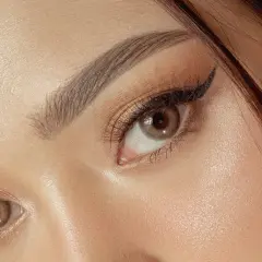 Un maquillage yeux sophistiqué avec un trait d'eye-liner fin et des fards dorés scintillants.