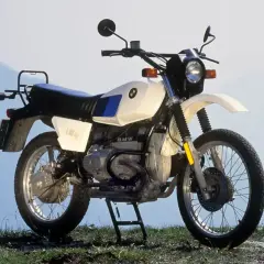 Una BMW R80GS, una icónica moto de los 80, lista para la aventura en un paisaje montañoso.
